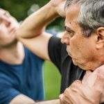 Kapap instructor demonstrates street fighting self defence technique against holds and grabs with his student. Martial arts