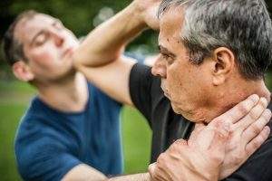 Kapap instructor demonstrates street fighting self defence technique against holds and grabs with his student. Martial arts
