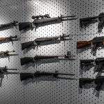Collection of rifles and carbines. Various firearms hang on special mounts on the wall. Weapon background.